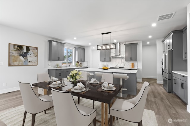 dining space with an inviting chandelier, sink, and light wood-type flooring