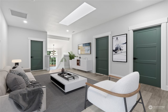 living room with a skylight, a chandelier, and hardwood / wood-style floors