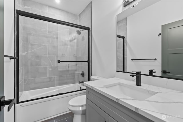 full bathroom with vanity, bath / shower combo with glass door, and toilet