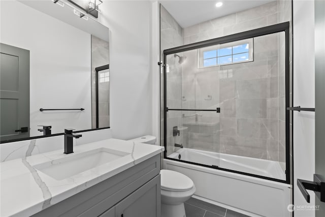 full bathroom with vanity, shower / bath combination with glass door, toilet, and tile patterned flooring