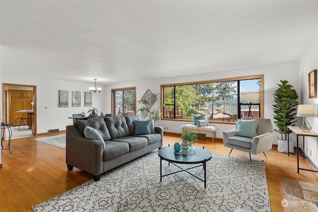 living room with light hardwood / wood-style flooring, plenty of natural light, and a chandelier