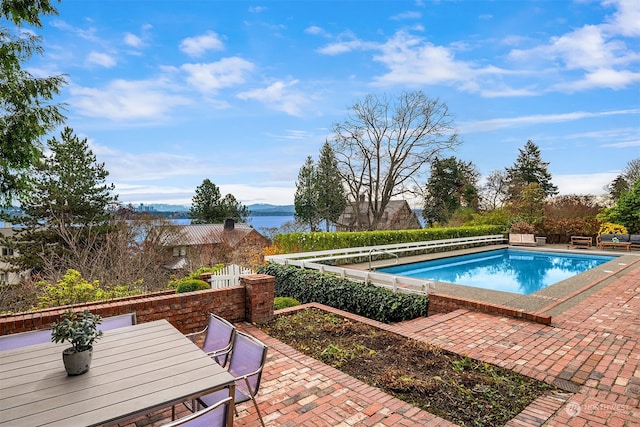 view of pool with a water view and a patio