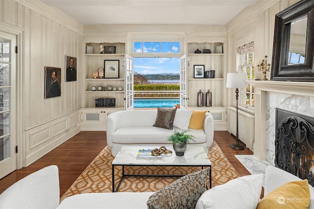 living room featuring built in features, a high end fireplace, dark hardwood / wood-style floors, and plenty of natural light