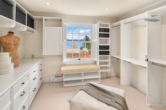 spacious closet with light carpet and a baseboard heating unit