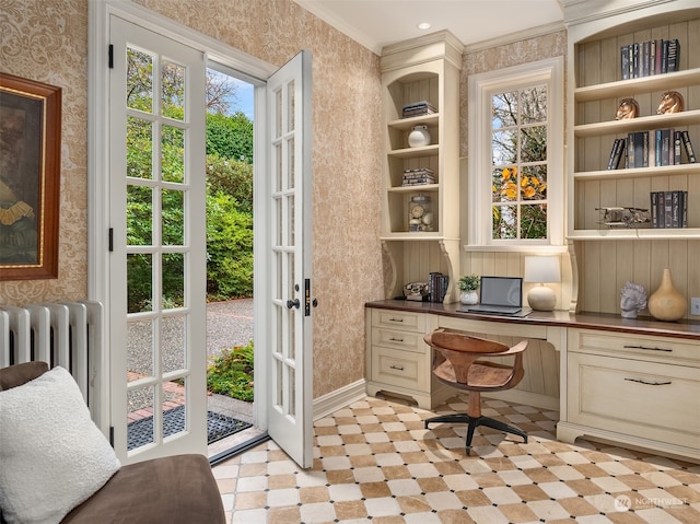 office featuring a healthy amount of sunlight, built in desk, crown molding, and radiator