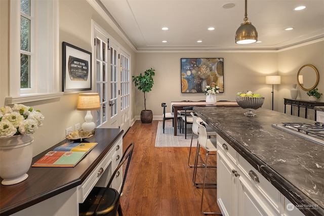 kitchen featuring white cabinets, a kitchen bar, decorative light fixtures, and dark wood-type flooring