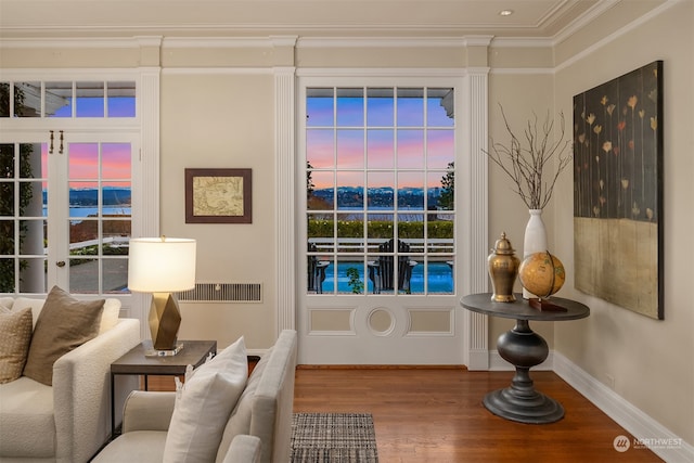 living area with hardwood / wood-style floors, a water view, and ornamental molding