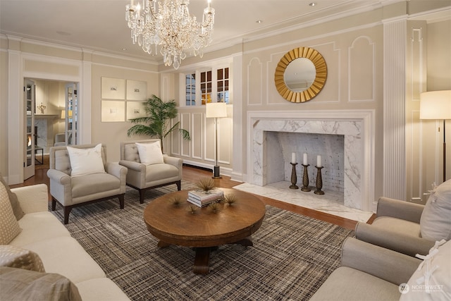 living room featuring wood-type flooring, ornamental molding, a high end fireplace, and an inviting chandelier