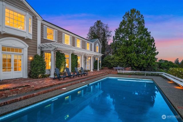 pool at dusk featuring a patio