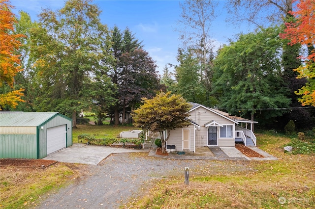 view of front of property with an outbuilding, covered porch, a front yard, and a garage