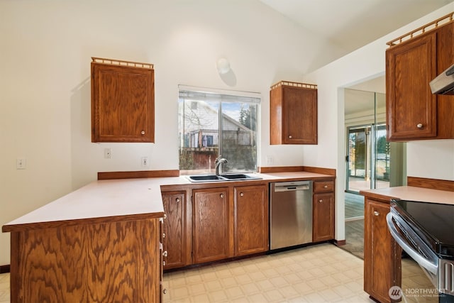 kitchen with sink, kitchen peninsula, appliances with stainless steel finishes, and vaulted ceiling