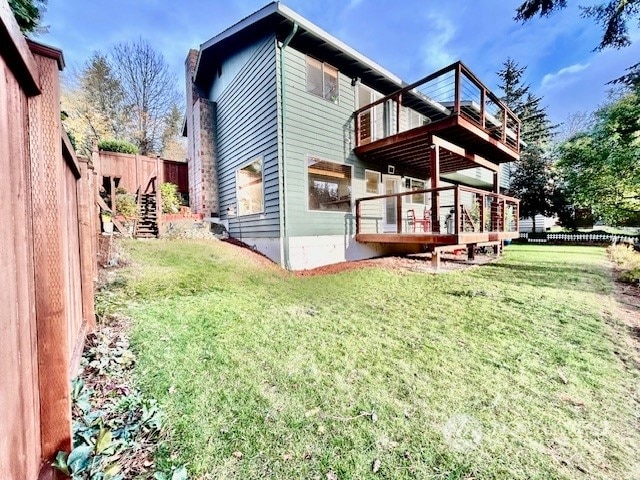 rear view of house with a lawn, a balcony, and a deck