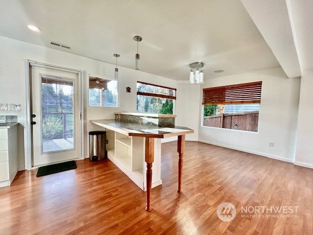 kitchen with kitchen peninsula, hanging light fixtures, and wood-type flooring