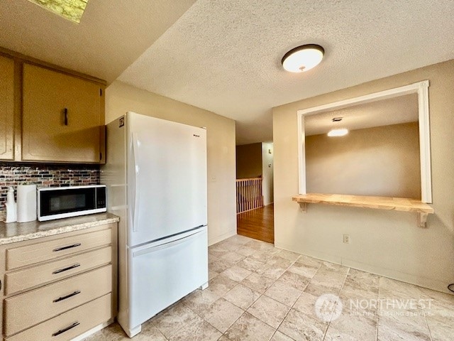 kitchen with white appliances and a textured ceiling