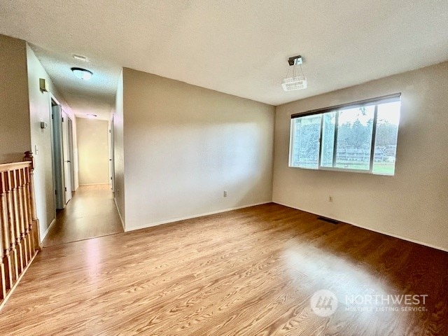 empty room with a textured ceiling and light hardwood / wood-style floors