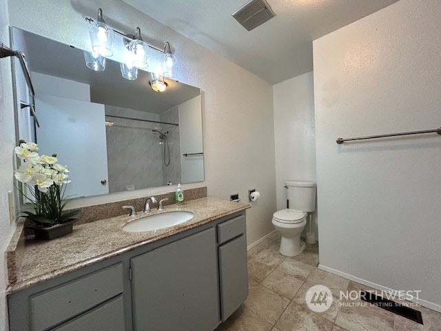 bathroom featuring a shower, vanity, toilet, and tile patterned flooring