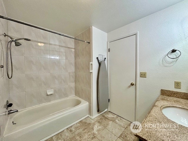 bathroom featuring tiled shower / bath combo, a textured ceiling, and vanity