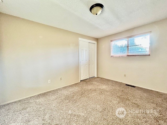 unfurnished bedroom with carpet flooring, a textured ceiling, and a closet