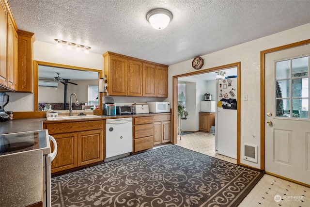 kitchen with sink, white appliances, a wealth of natural light, and a textured ceiling