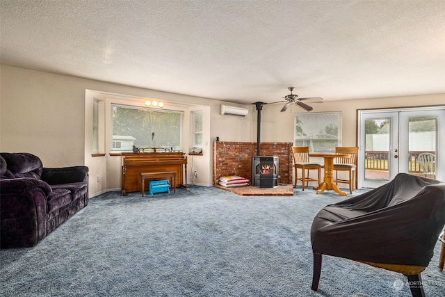 living room featuring ceiling fan with notable chandelier, a wood stove, carpet, and french doors