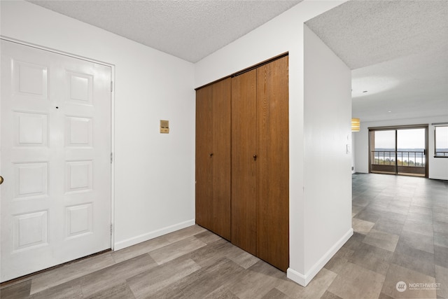 hall with a textured ceiling and light hardwood / wood-style floors