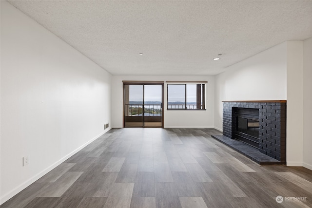 unfurnished living room featuring a fireplace, hardwood / wood-style flooring, and a textured ceiling