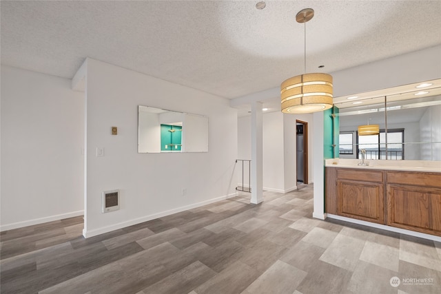 kitchen featuring pendant lighting, a textured ceiling, and light hardwood / wood-style flooring