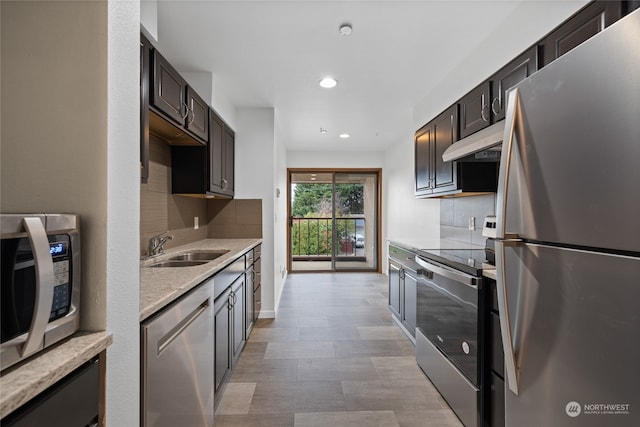 kitchen featuring appliances with stainless steel finishes, dark brown cabinetry, decorative backsplash, and sink