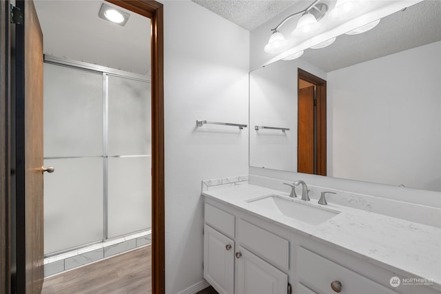 bathroom featuring walk in shower, hardwood / wood-style floors, vanity, and a textured ceiling