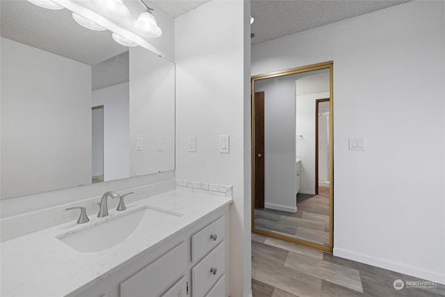 bathroom featuring hardwood / wood-style flooring, vanity, and a textured ceiling