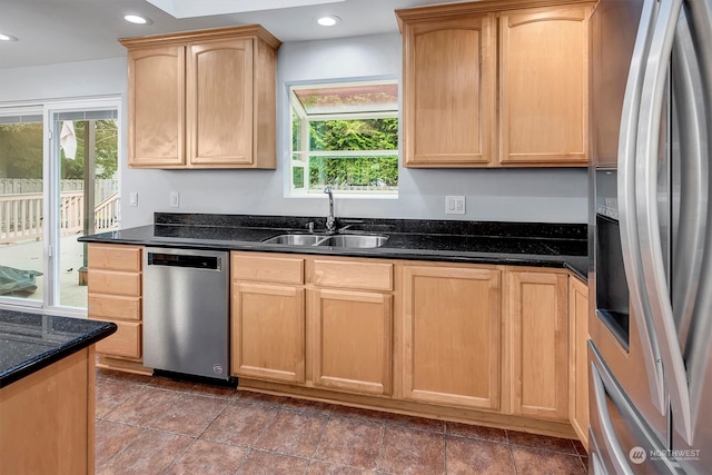 kitchen featuring dark tile patterned floors, light brown cabinets, dark stone counters, sink, and appliances with stainless steel finishes