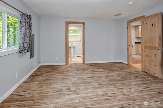 spare room with electric panel and light wood-type flooring