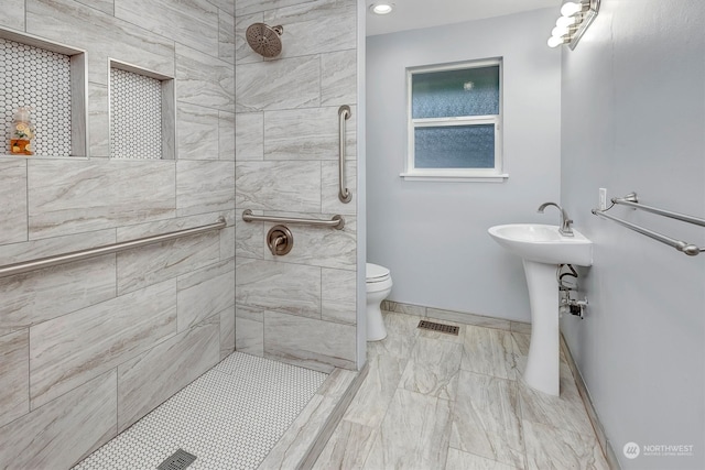 bathroom featuring a tile shower and toilet