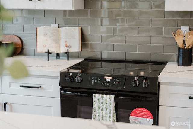 kitchen with electric range, backsplash, and white cabinets