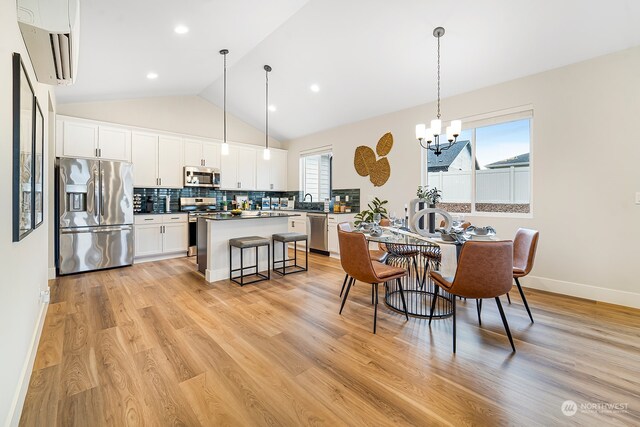 dining space with an AC wall unit, vaulted ceiling, light wood-type flooring, and a healthy amount of sunlight