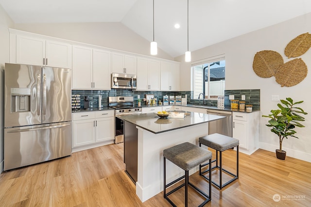 kitchen with white cabinets, stainless steel appliances, sink, and lofted ceiling