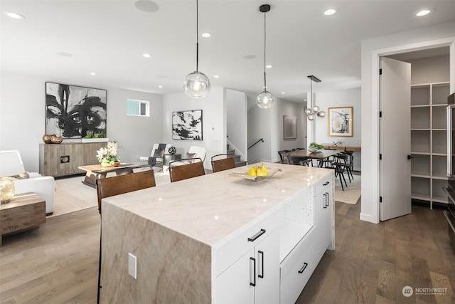 kitchen with pendant lighting, white cabinets, a center island, and dark wood-type flooring