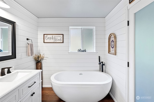 bathroom featuring vanity, hardwood / wood-style flooring, wooden walls, and a bathtub