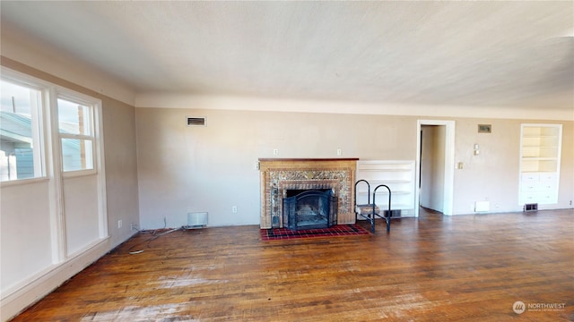 unfurnished living room with a tiled fireplace and dark hardwood / wood-style flooring