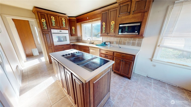 kitchen with appliances with stainless steel finishes, decorative backsplash, a center island, and sink