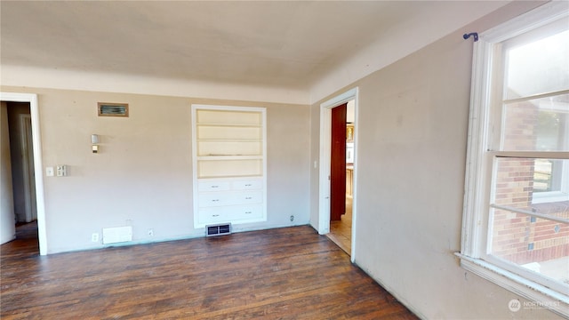 empty room featuring dark wood-type flooring and built in shelves