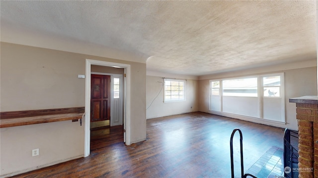 unfurnished living room with a textured ceiling, dark hardwood / wood-style flooring, and a fireplace