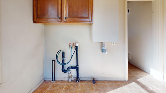 laundry room featuring hookup for a washing machine, light tile patterned floors, and cabinets