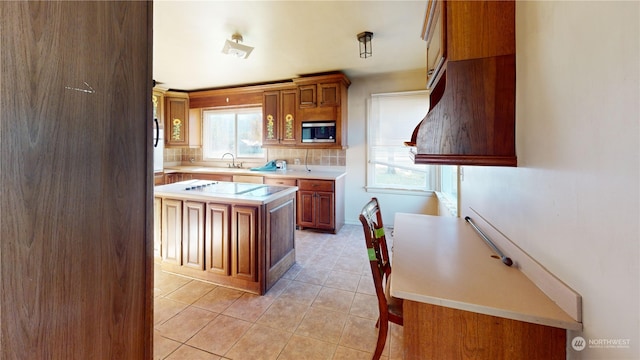 kitchen featuring stainless steel microwave, decorative backsplash, a center island, and light tile patterned floors