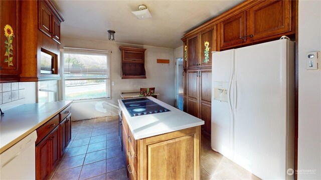 kitchen with white appliances, light tile patterned floors, and a kitchen island