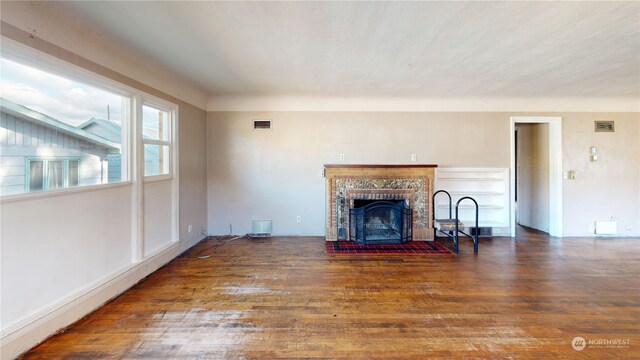 unfurnished living room with dark wood-type flooring and a brick fireplace