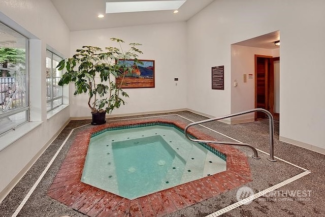 view of swimming pool with an indoor hot tub and a skylight