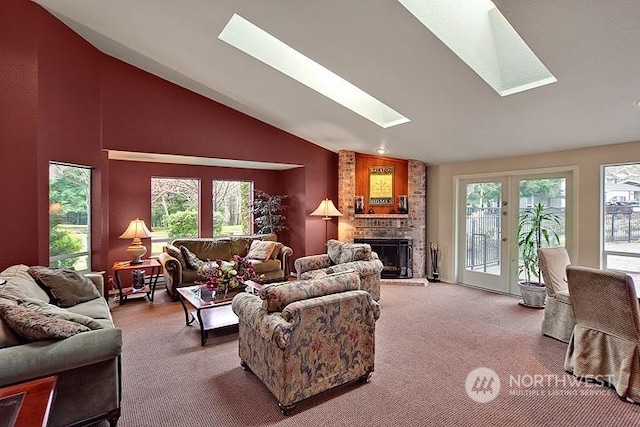 carpeted living room featuring high vaulted ceiling, a skylight, and a fireplace