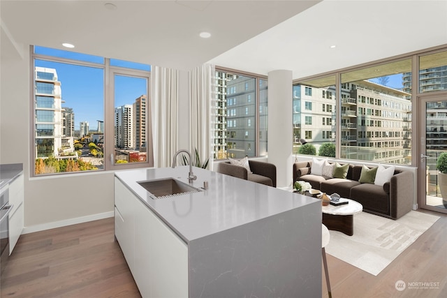 kitchen featuring white cabinetry, light hardwood / wood-style floors, a kitchen island with sink, and sink