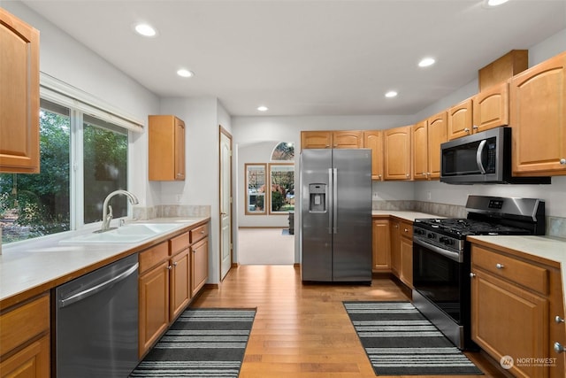 kitchen featuring stainless steel appliances, sink, and light wood-type flooring